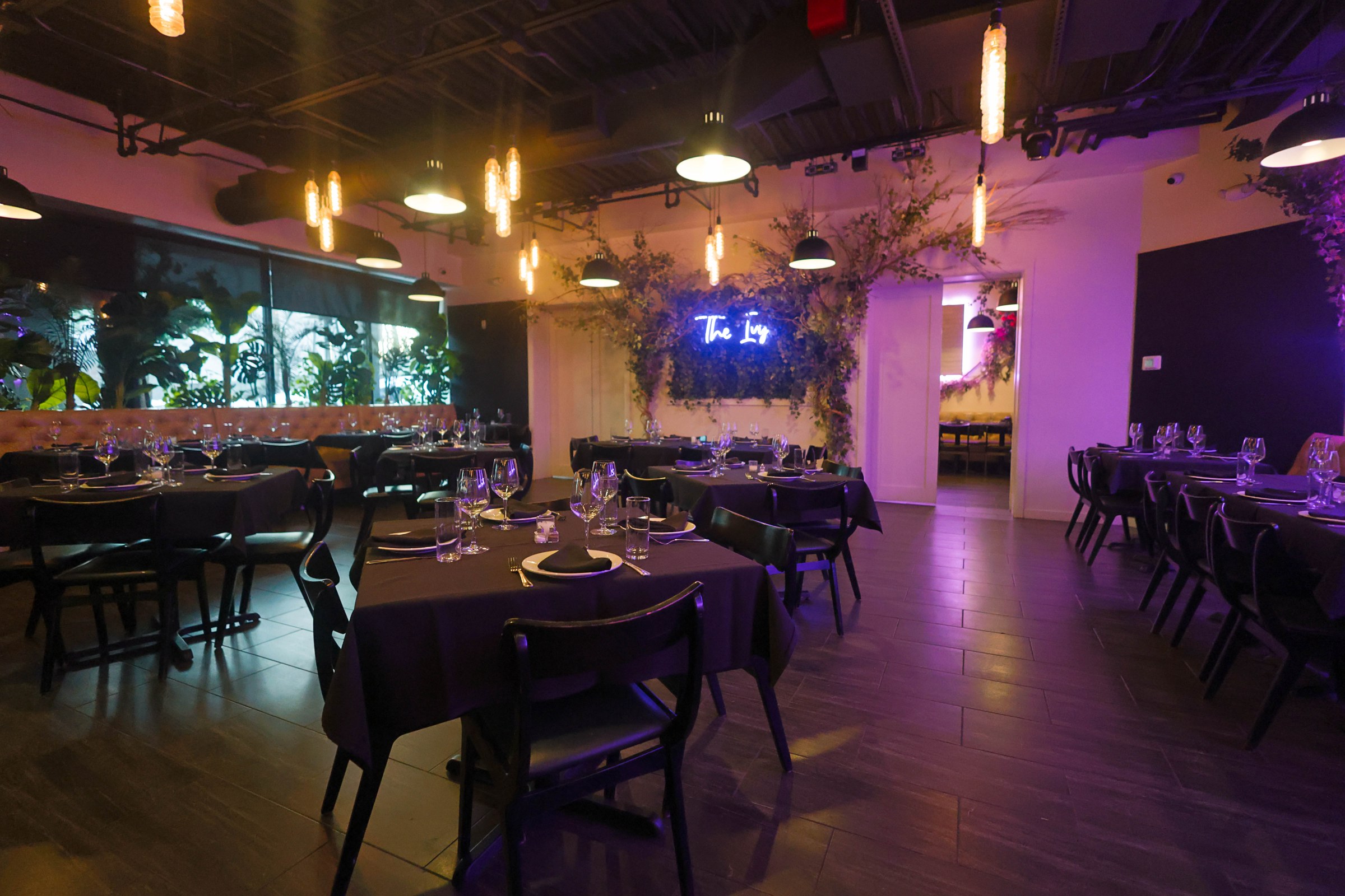 Ivy Huntington dining room with set tables, foliage and the illuminated Ivy sign