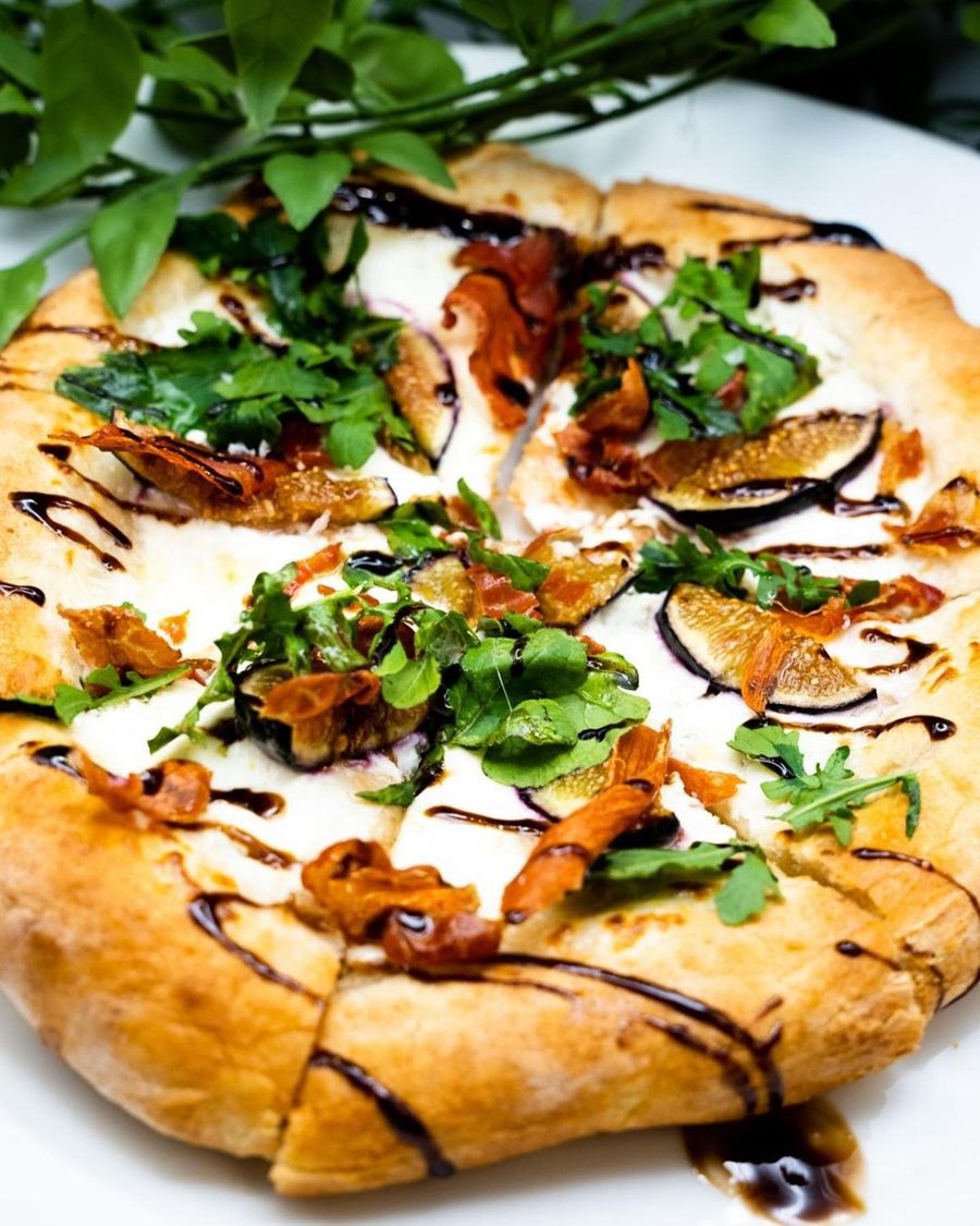 Flatbread-style dish with leafy toppings on a white plate